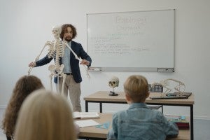 male teacher showing skeleton to students in science class
