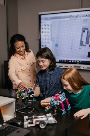 teacher helping students with toy robots