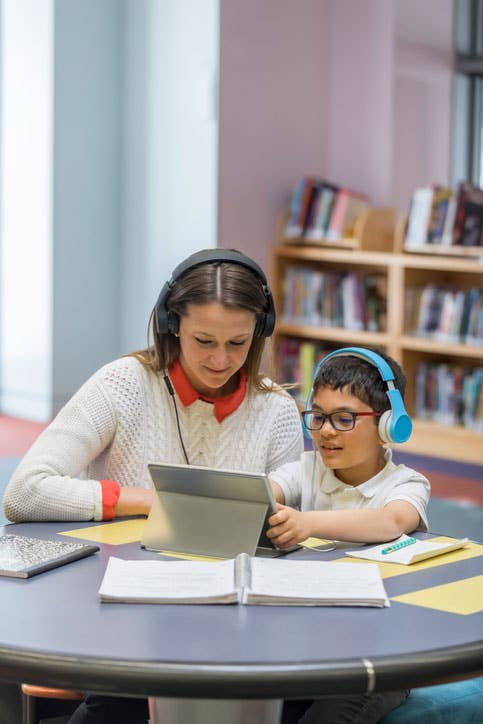 Student and teacher listening with headphones and using a tablet