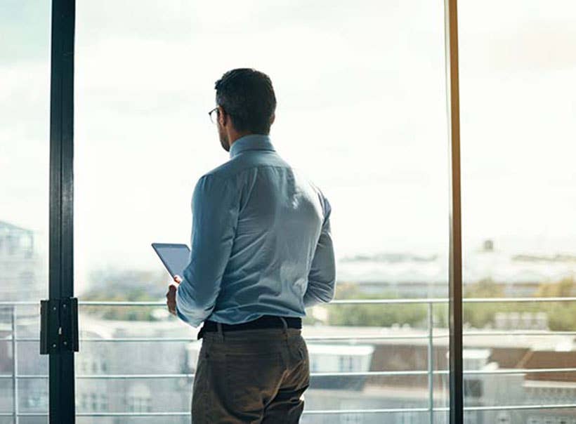 Rearview shot of a mature businessman looking out the window in an office