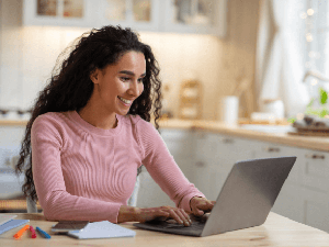 Woman in kitchen working at laptop