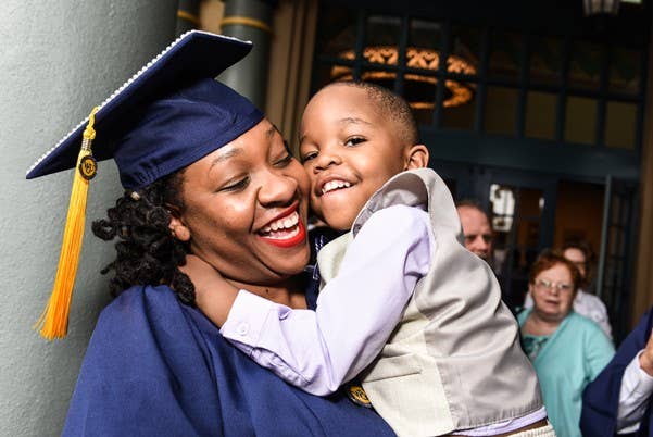 WGU graduate holding her son and smiling at graduation