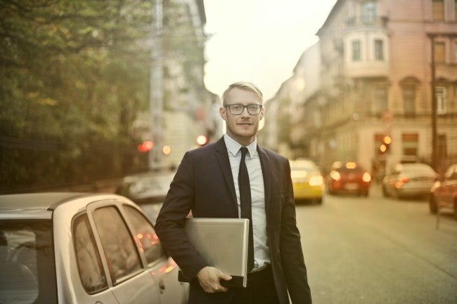 Man walking the streets new york while caring his laptop dressed in business attire