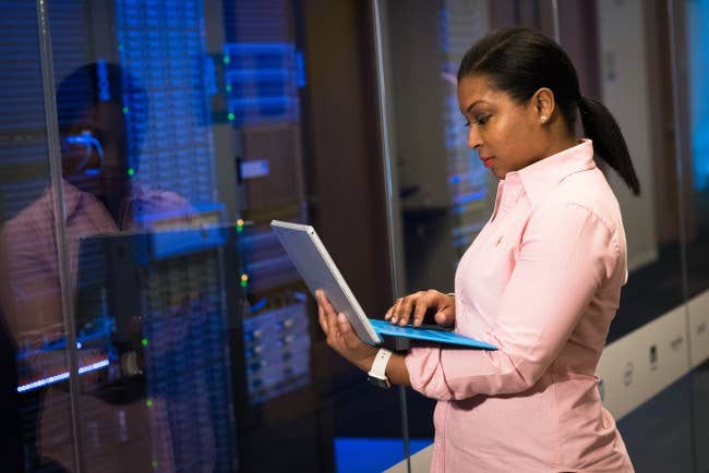 Woman holding computer next to large network