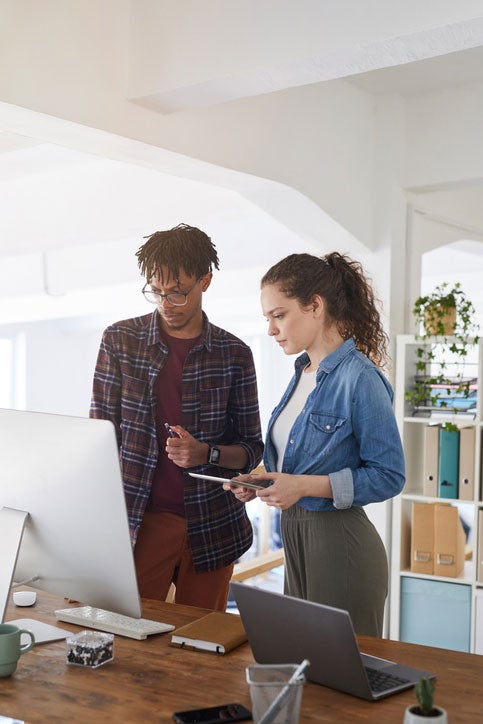 Two young IT professionals look at a large monitor