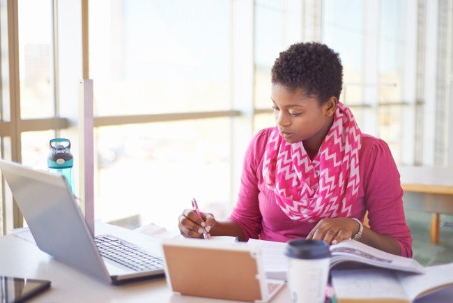 Woman working remotely with a phone connected to the laptop