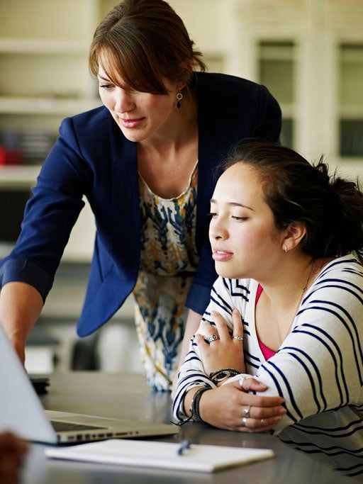 Teacher giving instruction to a student on a computer
