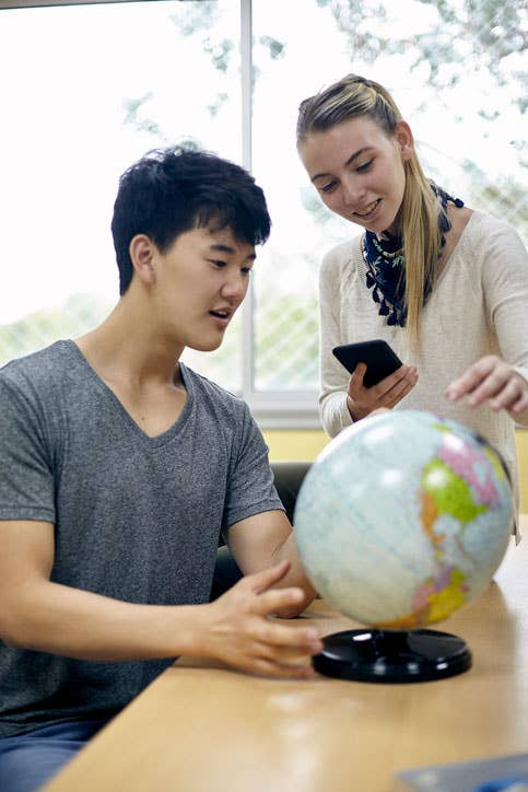 Two students look at a globe