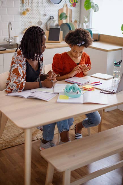 Mother and daughter work on schoolwork at a kitchen table