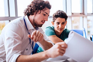 Male teacher talking about a paper with a student