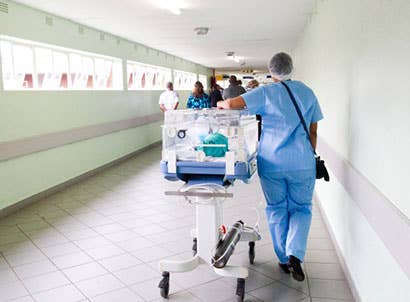 Nurse pushing baby in incubator through the hall of a hospital