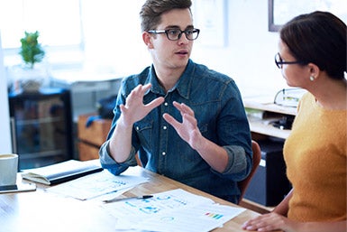 Two professionals discussing a project while sitting at a desk