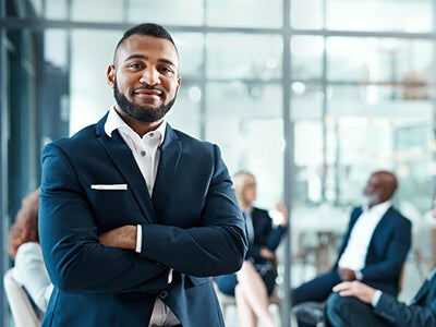 Man standing with arms crossed and smiling in a office setting