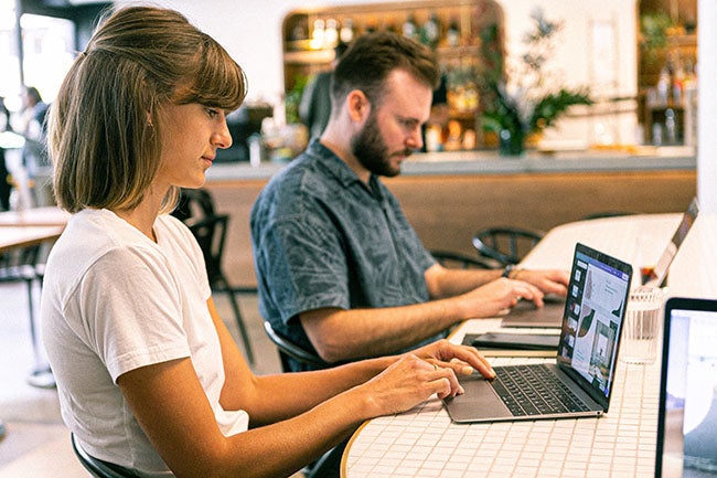 Woman and man typing on laptop computers at desk