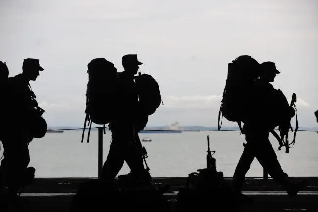 Shadowy view of military people walking across a bridge