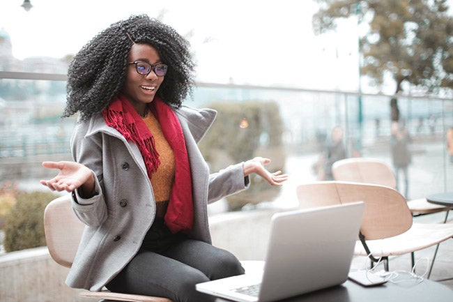 Woman wearing glasses and coat talking on a video call on laptop