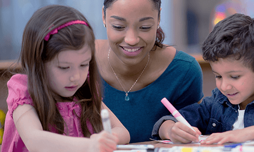 Elementary teacher sits with two young students.