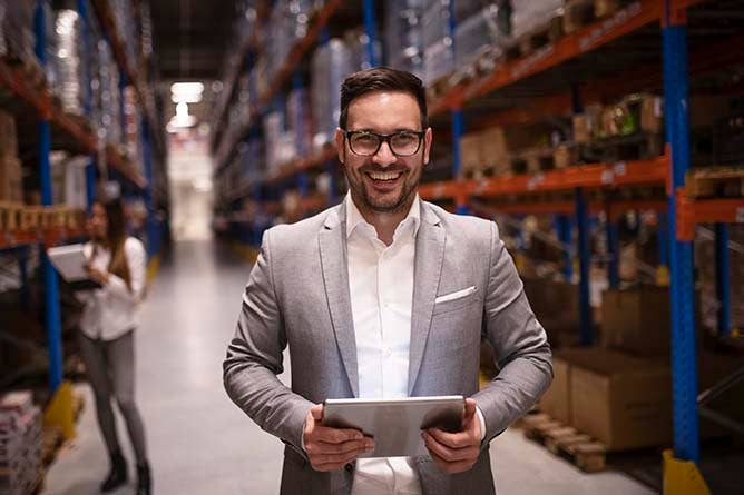 Man smiling and holding clipboard in a warehouse
