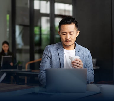 Man looking at his laptop while drinking coffee