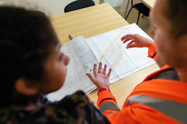 engineer in safety suit explaining work details to colleague