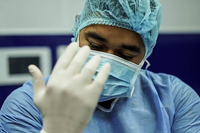 Medical professional putting on surgical scrubs and gloves