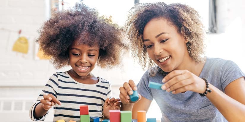 Toddler and teacher playing with blocks together