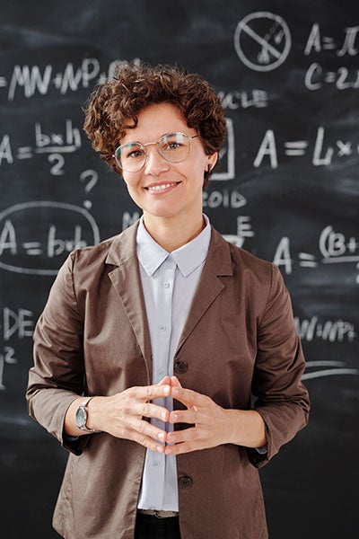 Woman pictured in front of a blackboard showing math formulas