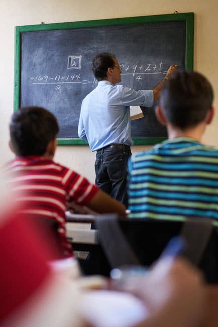 Math teacher writes equations on a blackboard