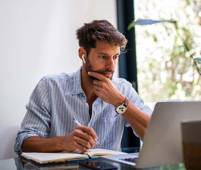 Man studying at laptop with headphones in his ears