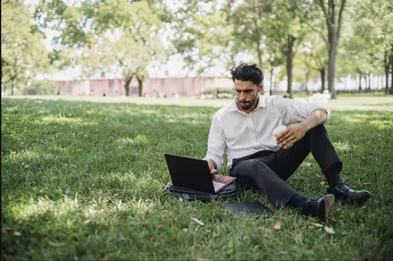 Man sitting outside on ground with laptop