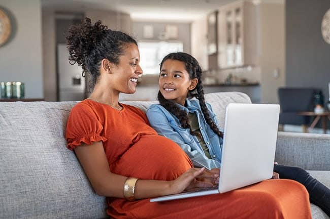 Pregnant woman on computer with daughter