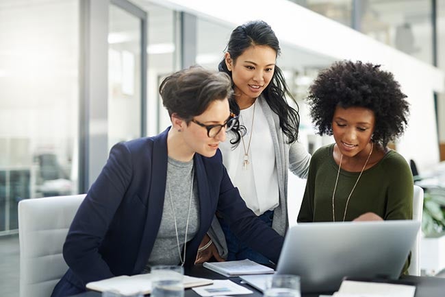 Shot of a group of businesswomen using a laptop during a meeting at work