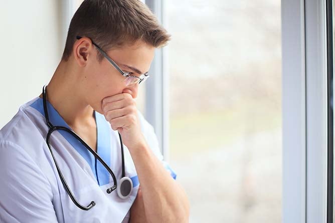 Photo of pensive nurse thinking near a window