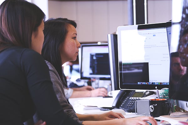 Two IT professionals working on a computer together