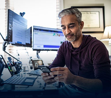 Man looking at his smartphone while sitting at a desk 