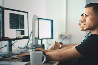 Two IT professionals working at desks next to each other