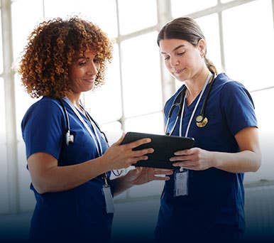 Two nurses discussing patient information on tablet
