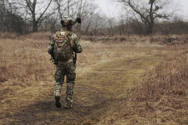 Military person walking through a field