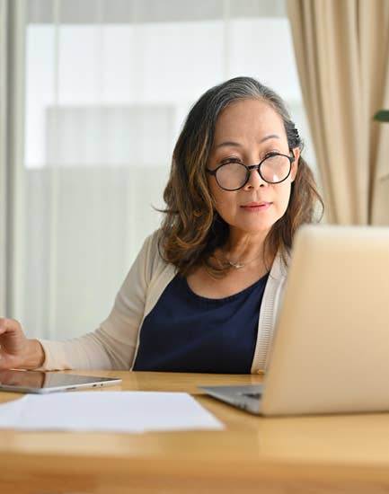 Woman working on laptop and writing down notes