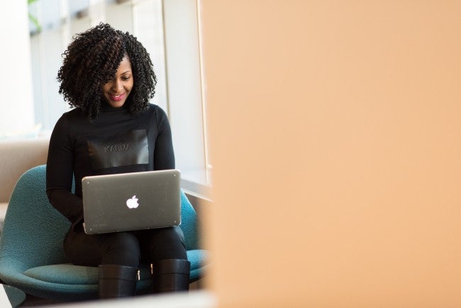 Smiling woman working on laptop in her lap