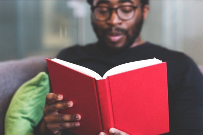 Man with glasses holding a red book