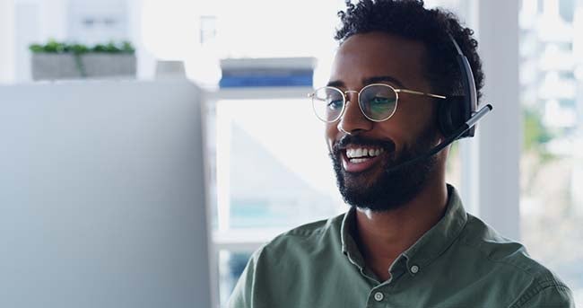 Shot of a handsome young businessman wearing headsets while working on a computer in his office