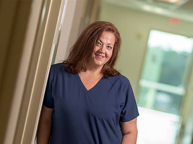Laurie Charles, pictured in a hospital hallway, wearing scrubs.